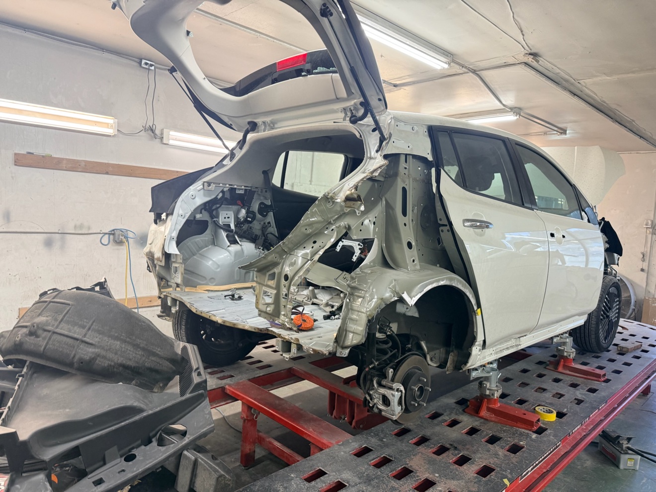 Nissan Leaf stripped to the rear body structure on a frame machine during repair / Nissan Leaf desmontado hasta la estructura trasera en una bancada durante la reparación